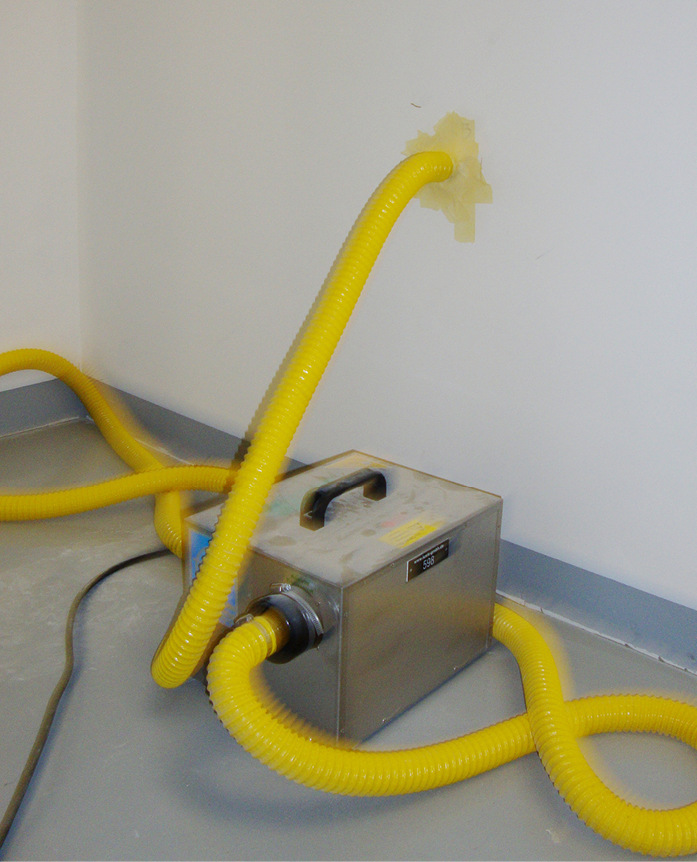 Abb. 3:  Bautrockner mit Schlauch in die Kommunwand (Pumpenaktivität durch vibrierenden Schlauch erkennbar)