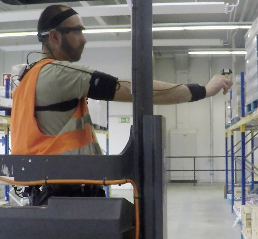 Abb. 3: Nutzung einer AR-Datenbrille in Kombination mit einem Ringscanner bei der Kommissionierung im Lager, während der Mitarbeiter mit dem CUELA-Messsystem zur Haltungsanalyse ausgestattet ist