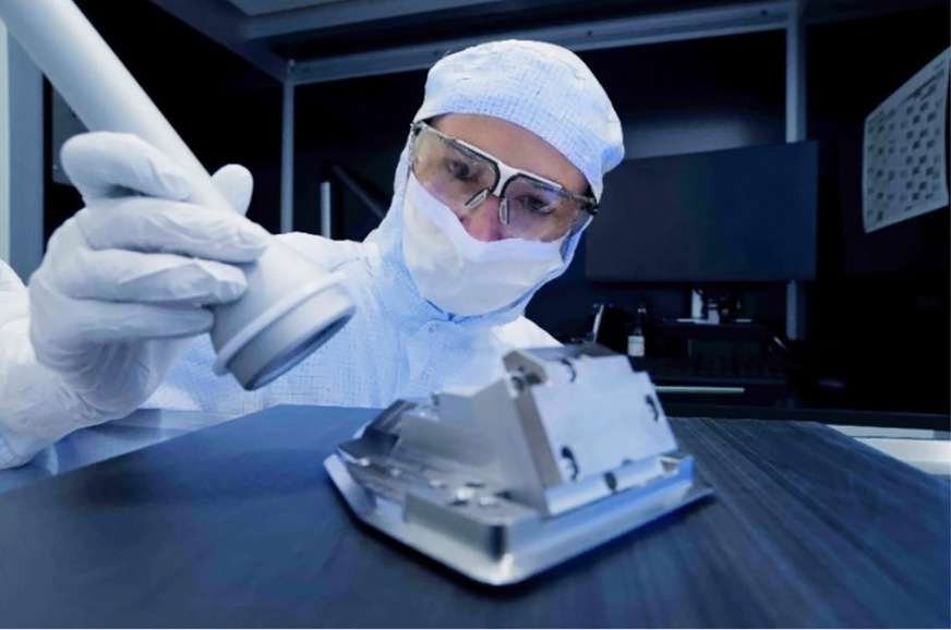 Abb. 1:  Mitarbeitender in kompletter PSA-Ausrüstung während der Tätigkeit mit einer UV-A-Lampe im Reinraum