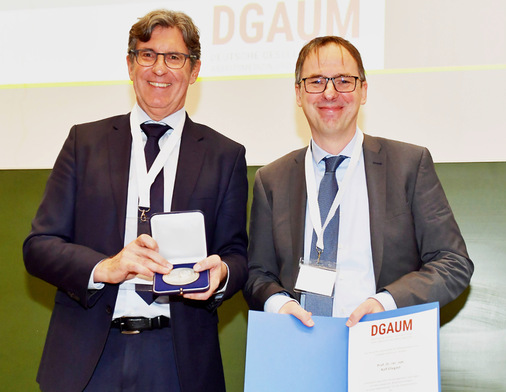 Prof. Thomas Kraus (links) verleiht Prof. Rolf Ellegast (rechts) die ­Joseph-Rutenfranz-Medaille