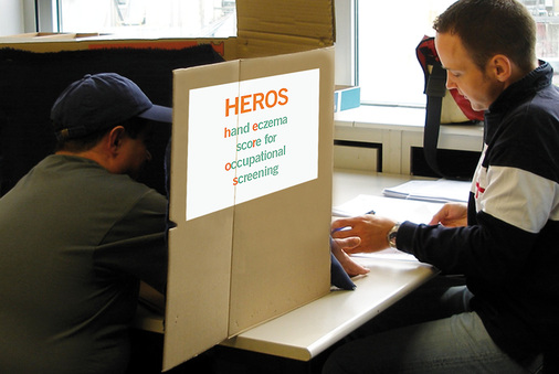 
 Abb. 3: 
 HEROS – Untersuchungen zur Intraobserver-Variabilität. Zu untersuchende Person hinter einem Sichtschutz, die Hände durch ein Untersuchungsfenster streckend
