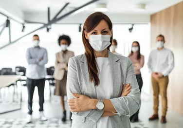 „Gruppe von Fachleuten für Arbeitssicherheit und Gesundheitsschutz, maskiert und in Geschäftskleidung, diskutiert präventive Maßnahmen zur Verbesserung der Betriebsgesundheit. - © bnenin – stock.adobe.com