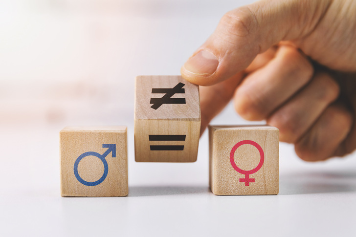 gender equality and discrimination concept - hand putting wooden blocks with symbols