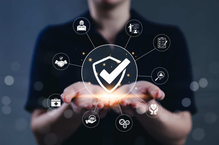 Work safety and compliance management concept. A person holds a shield check surrounded by safety, compliance, and risk assessment symbols, representing occupational health and workplace regulations.