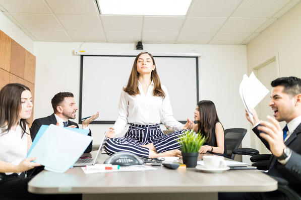 Alt-Text: „Eine Fachkraft für betriebliches Gesundheitsmanagement demonstriert Achtsamkeitsübungen zur Stressreduktion im Arbeitsumfeld, während Mitarbeiter im Hintergrund eine Diskussion führen.“. - © iStock – Pressefotot BGF-Koordinierungsstelle