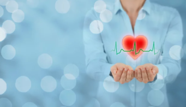 Alt-Text: „Illustration eines leuchtenden Herzens mit EKG-Linie, symbolisiert präventive Gesundheitsmaßnahmen im betrieblichen Gesundheitsmanagement, vor einem blauen Bokeh-Hintergrund. - © jirsak – stock.adobe.com