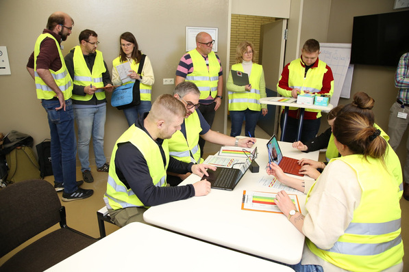 „Betriebsärzte und Gesundheitsmanager in Warnwesten arbeiten an einem Tisch zusammen, vertiefen sich in Laptops und Dokumente rund um Arbeitsschutzmaßnahmen und Prävention. - © BG Klinik Ludwigshafen/Geir Dillan